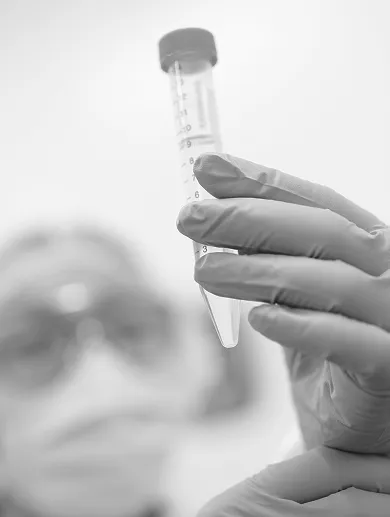 Black and white close-up of a gloved hand holding a syringe