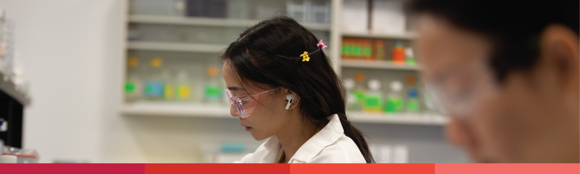Close-up profile of two lab workers wearing safety goggles in a lab