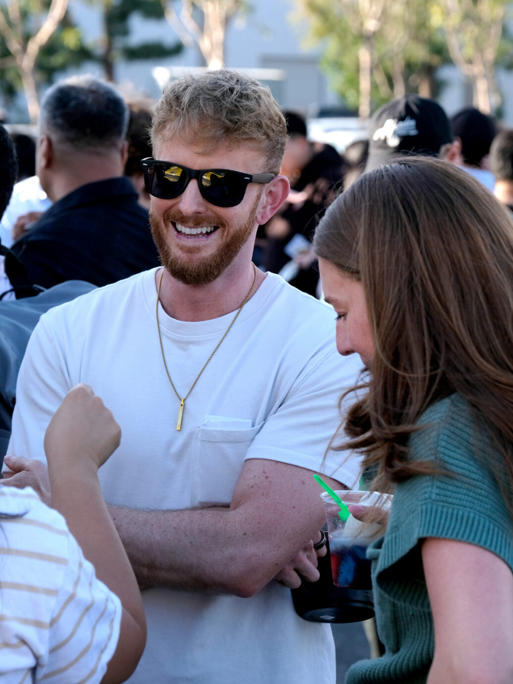 Smiling man wearing sunglasses in a crowd outdoors
