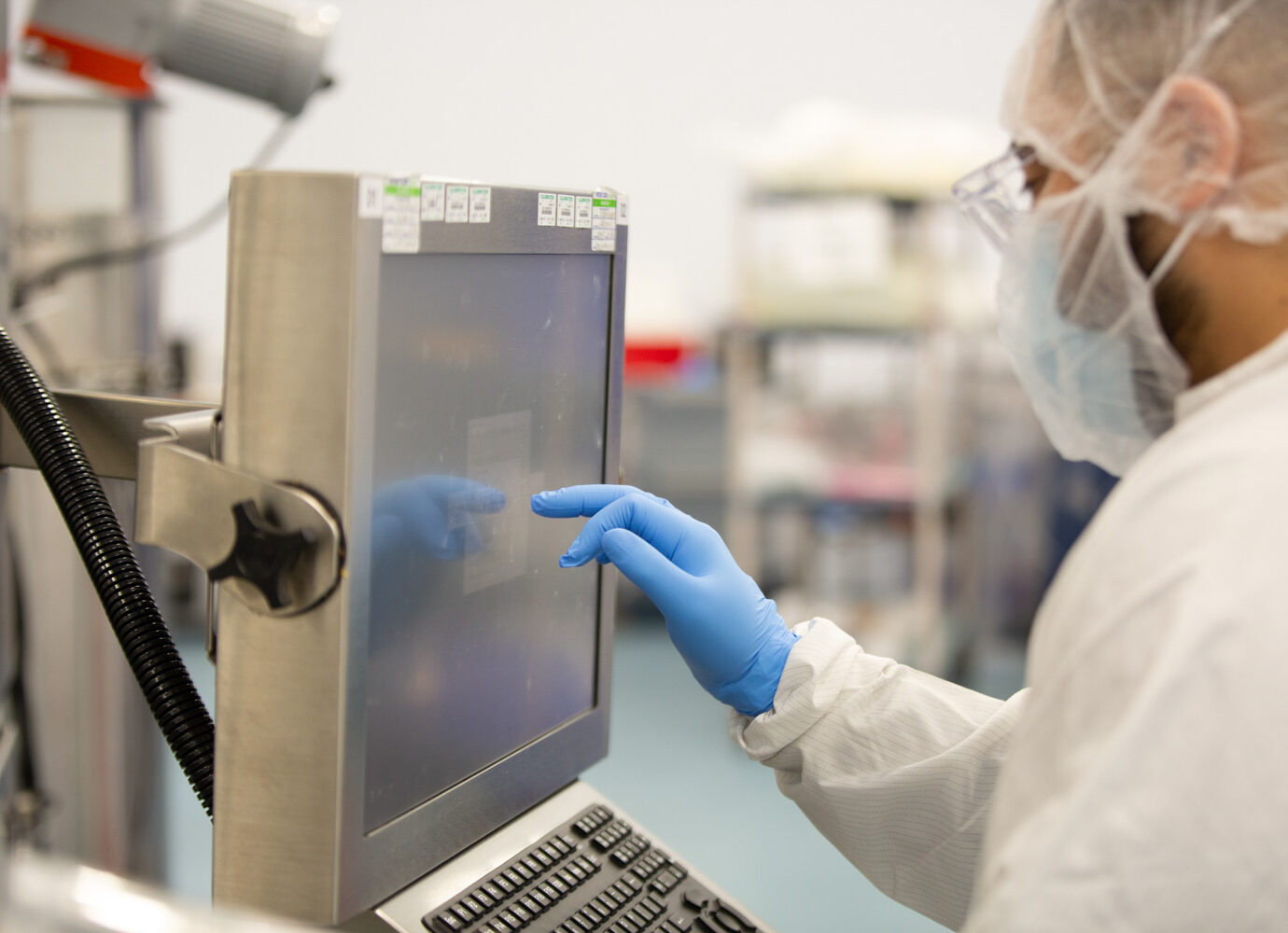 Cleanroom technician adjusting a manufacturing equipment control panel