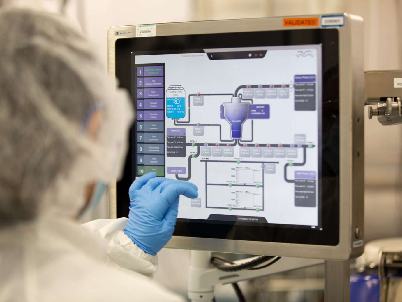 Technician in gloves monitoring a bioprocess control system touchscreen showing a validated process diagram