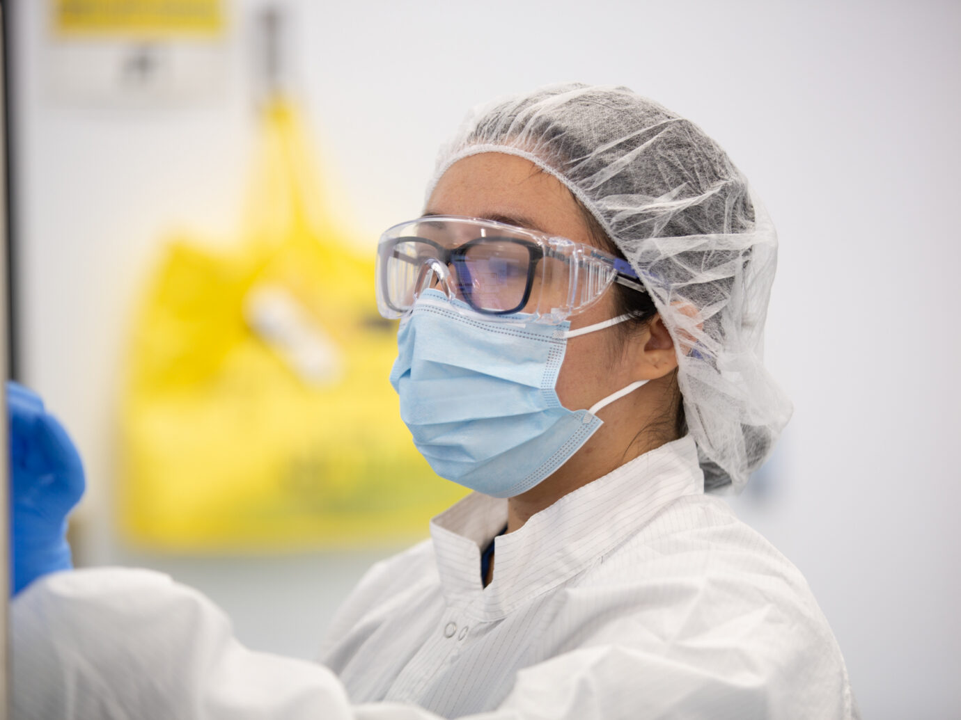Cleanroom technician wearing a hairnet, safety glasses, and mask