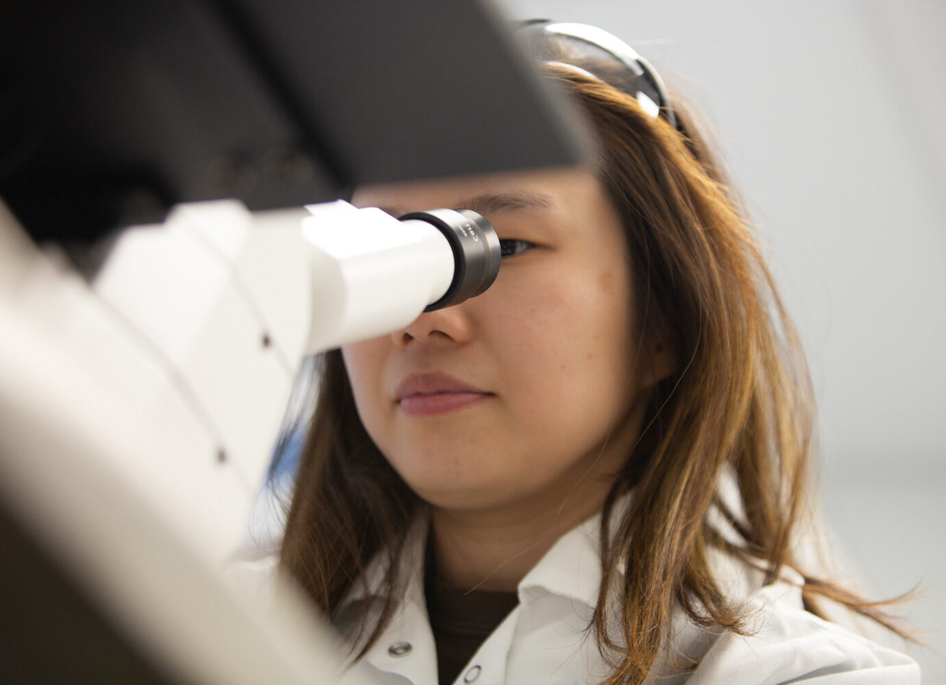 Woman looking through a microscope in a laboratory