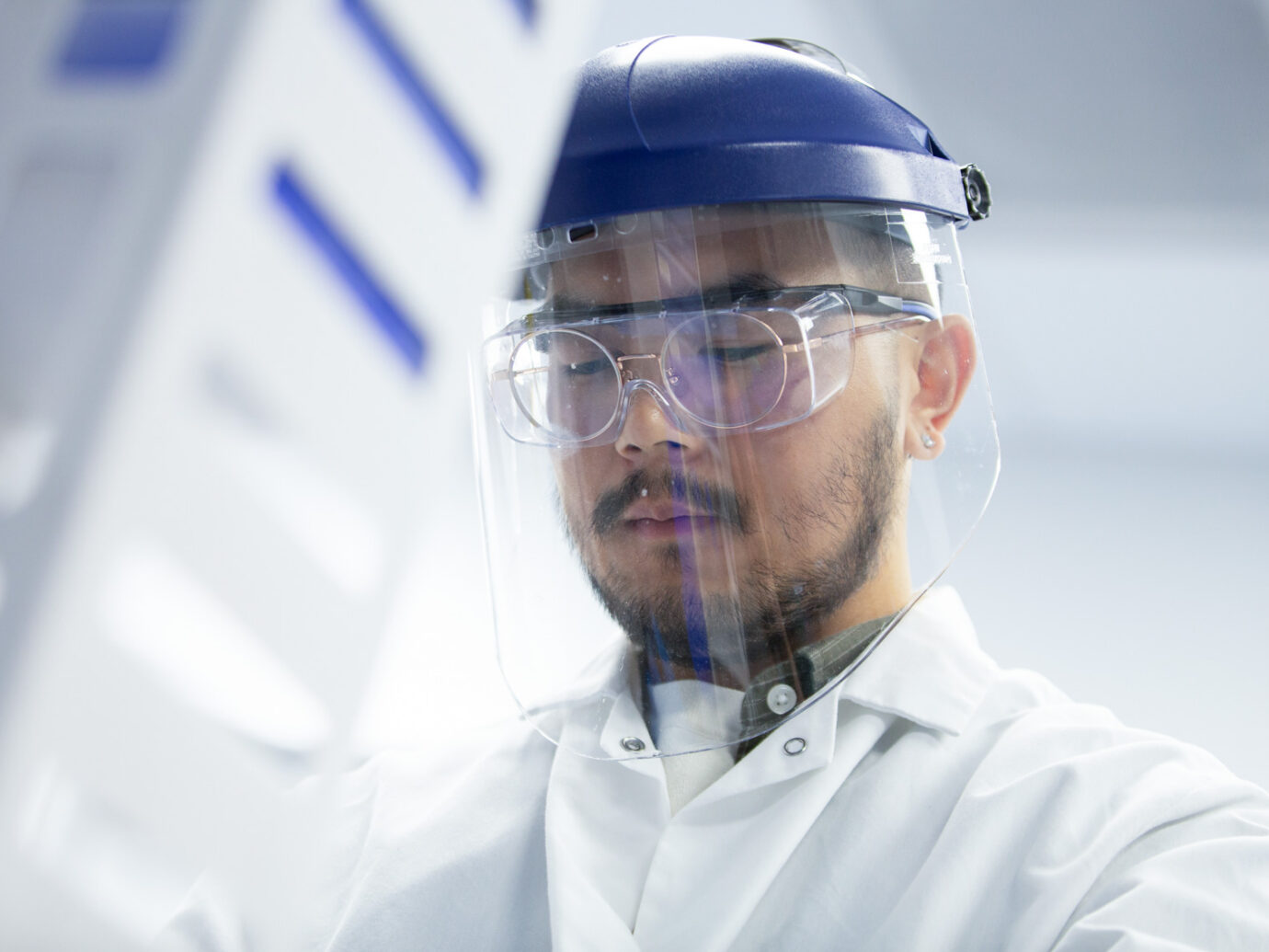 Close-up of a worker wearing a face shield and safety goggles with a hard hat