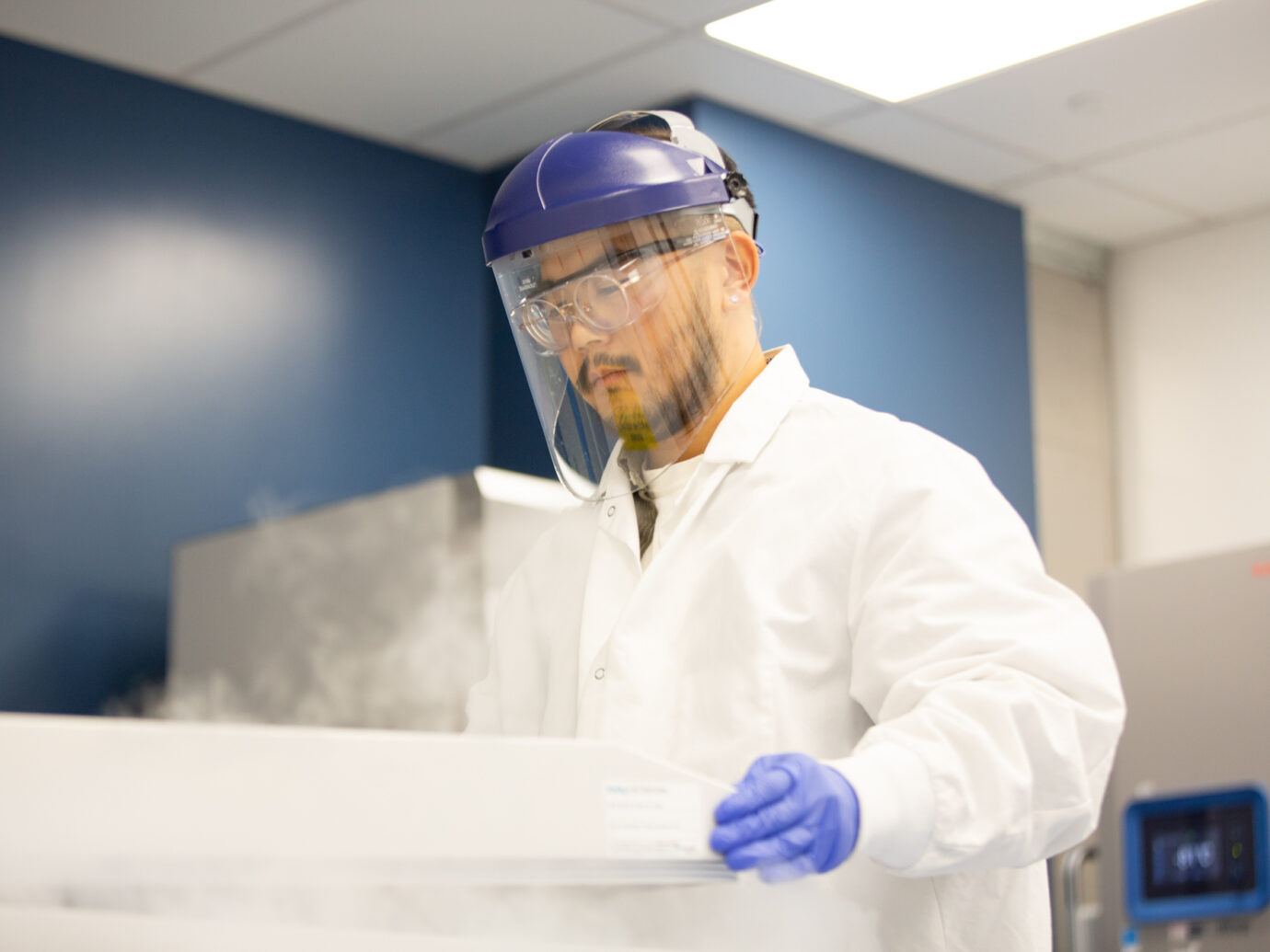 Male worker wearing a face shield and hard hat in a facility