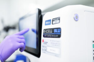 Gloved hand operating a Vi-CELL BLU cell viability analyzer