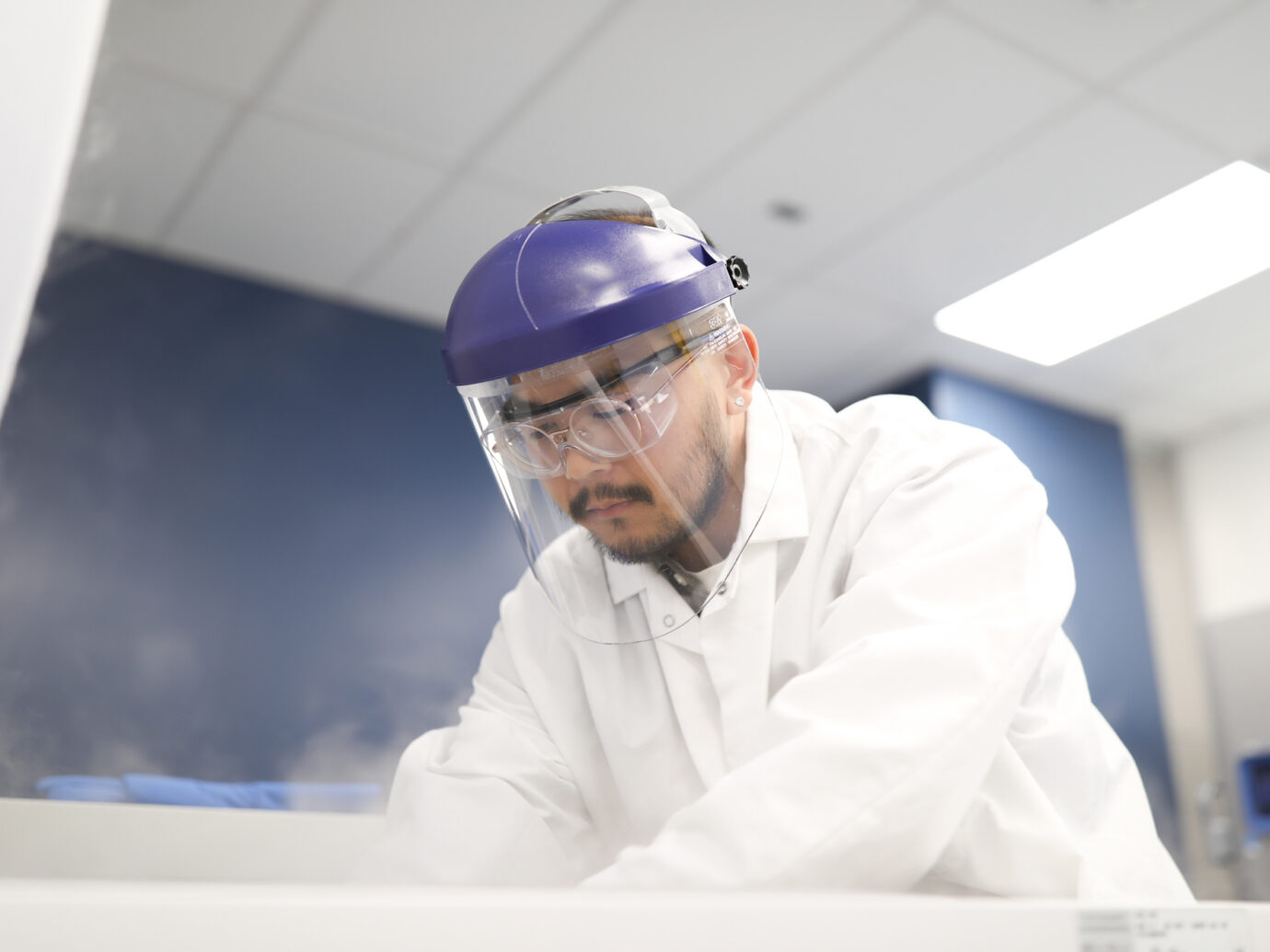 Man wearing a purple face shield and safety glasses in a laboratory