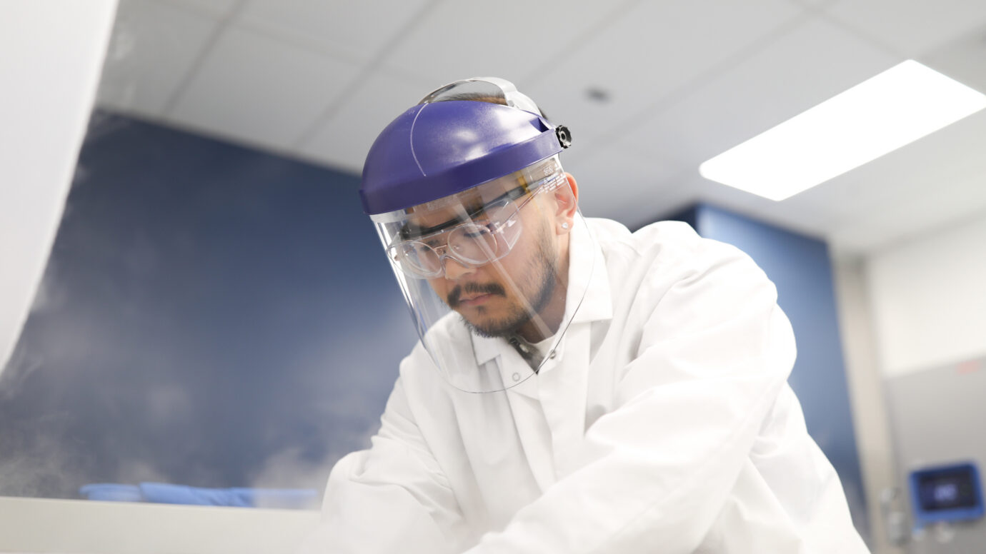 Man wearing a purple face shield and safety glasses in a laboratory