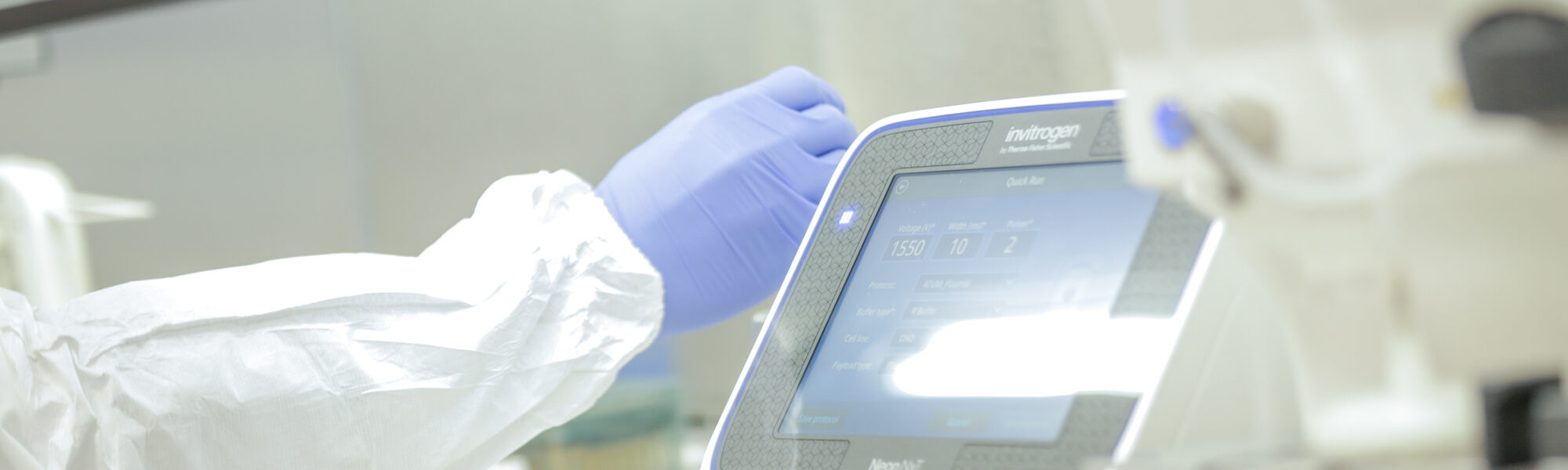 Gloved hand operating a touchscreen instrument panel in a lab