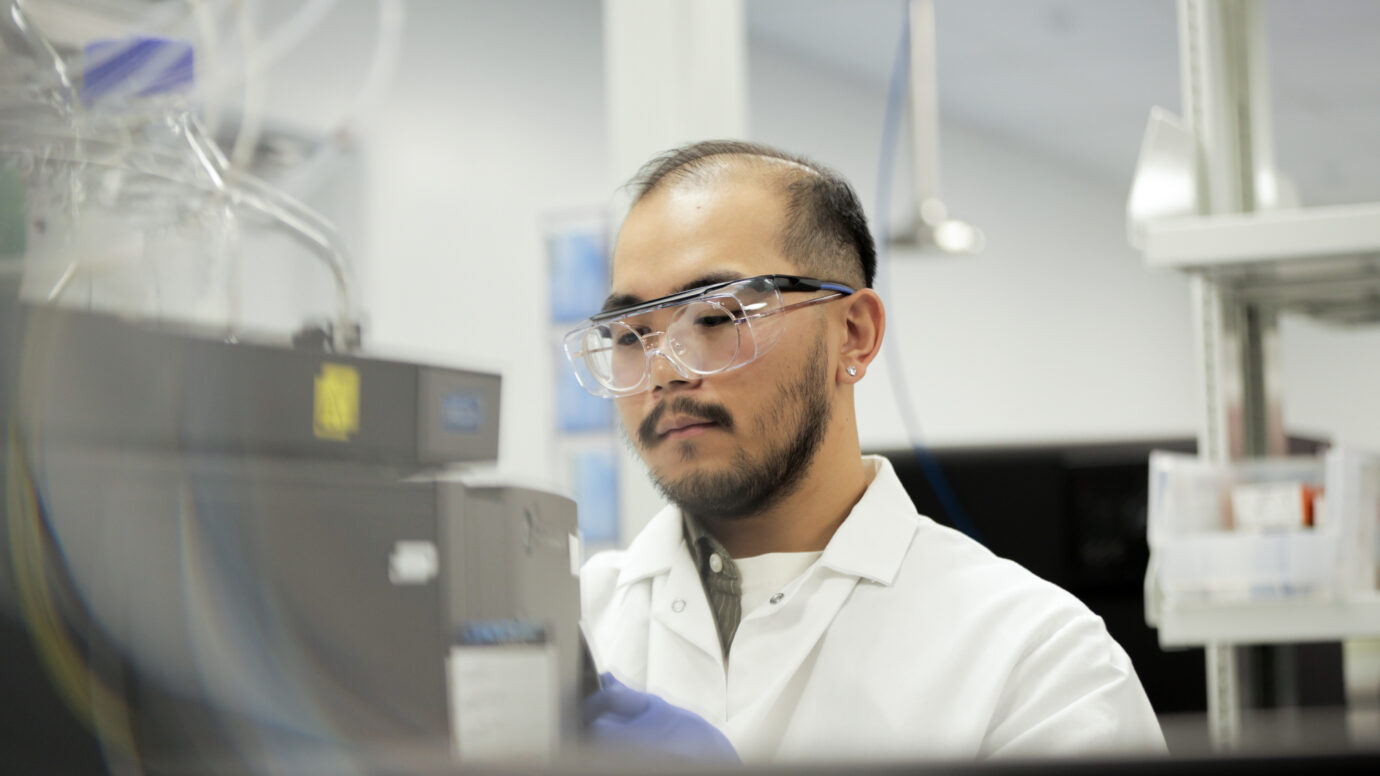 Man with a beard wearing safety glasses in a laboratory