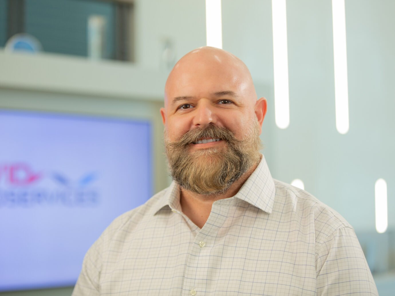 Smiling bald man with a full beard in an office setting