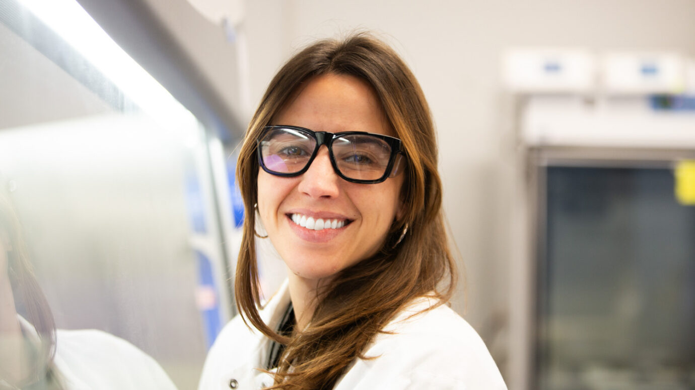 Smiling woman wearing dark-framed glasses in a facility