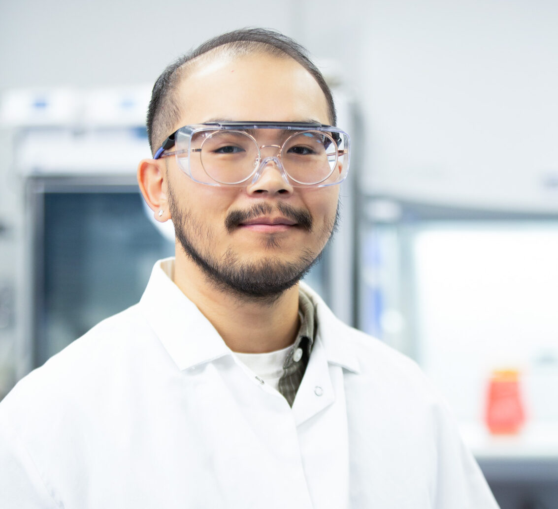 Man with a beard wearing safety glasses in a manufacturing facility