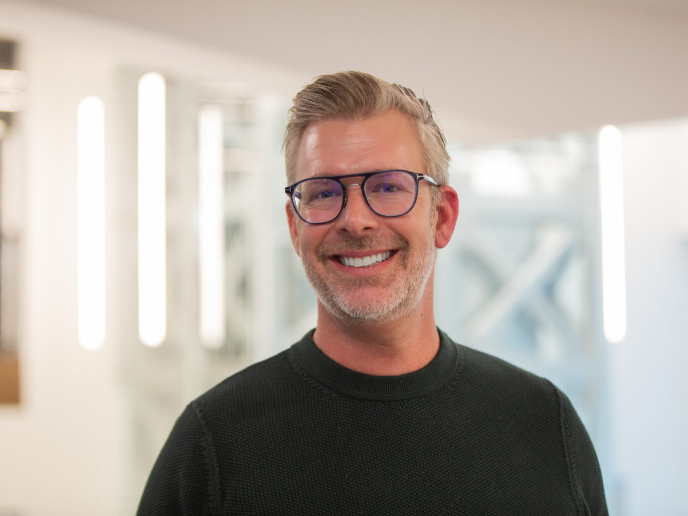 Smiling man with grey hair wearing glasses in an office