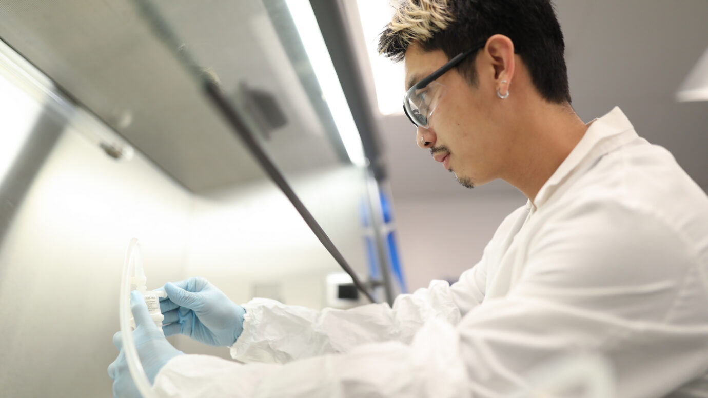 Male lab worker with glasses focused on equipment in a laboratory
