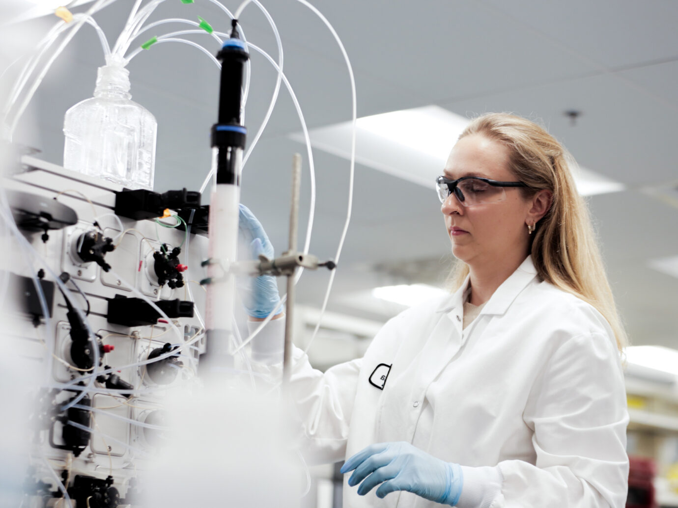 Female scientist observing bioprocessing equipment with tubing in a lab