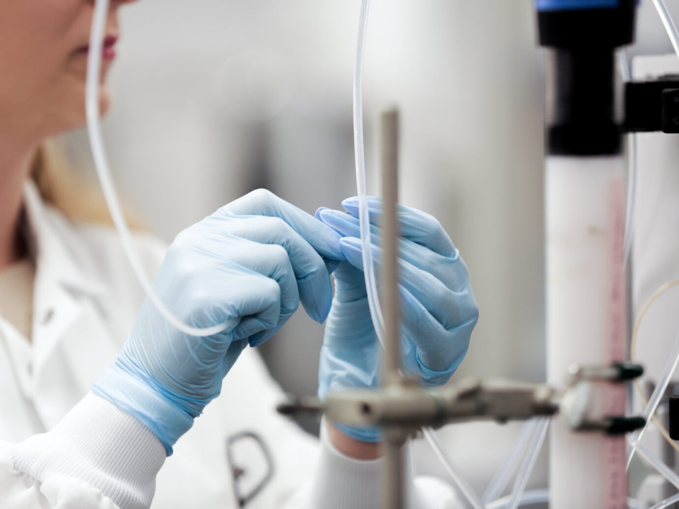 Lab technician in gloves connecting tubing to laboratory equipment