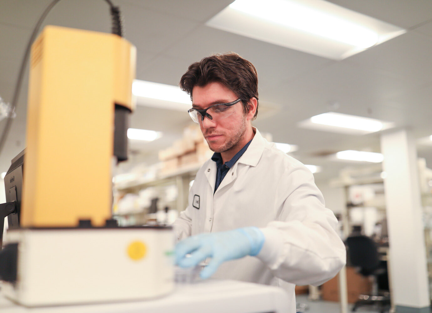 Man wearing safety glasses examining laboratory equipment