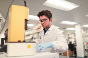 Man wearing safety glasses examining laboratory equipment