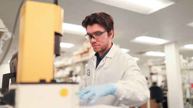 Man wearing safety glasses examining laboratory equipment