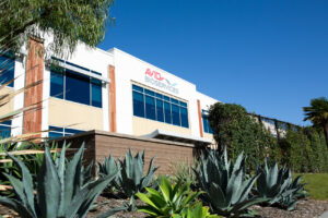 Exterior of an Avid Bioservices manufacturing building with a palm tree