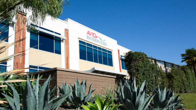 Exterior of an Avid Bioservices manufacturing building with a palm tree