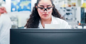 Female scientist wearing safety glasses reviewing a document in a lab
