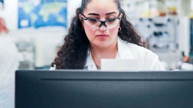 Female scientist wearing safety glasses reviewing a document in a lab