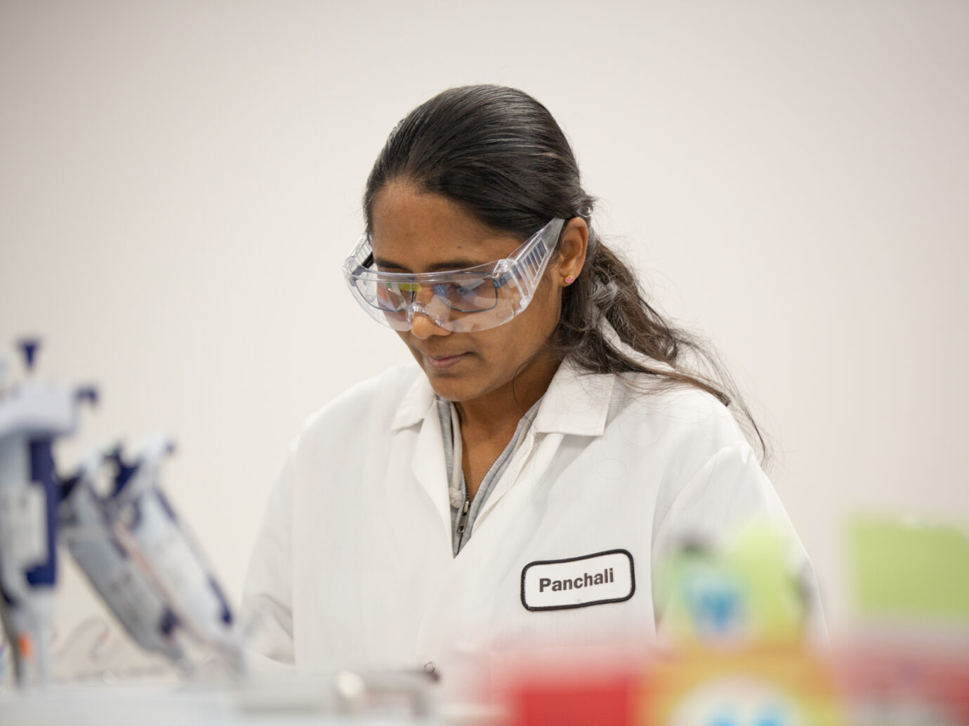 Female lab worker wearing safety goggles focused on work in a laboratory