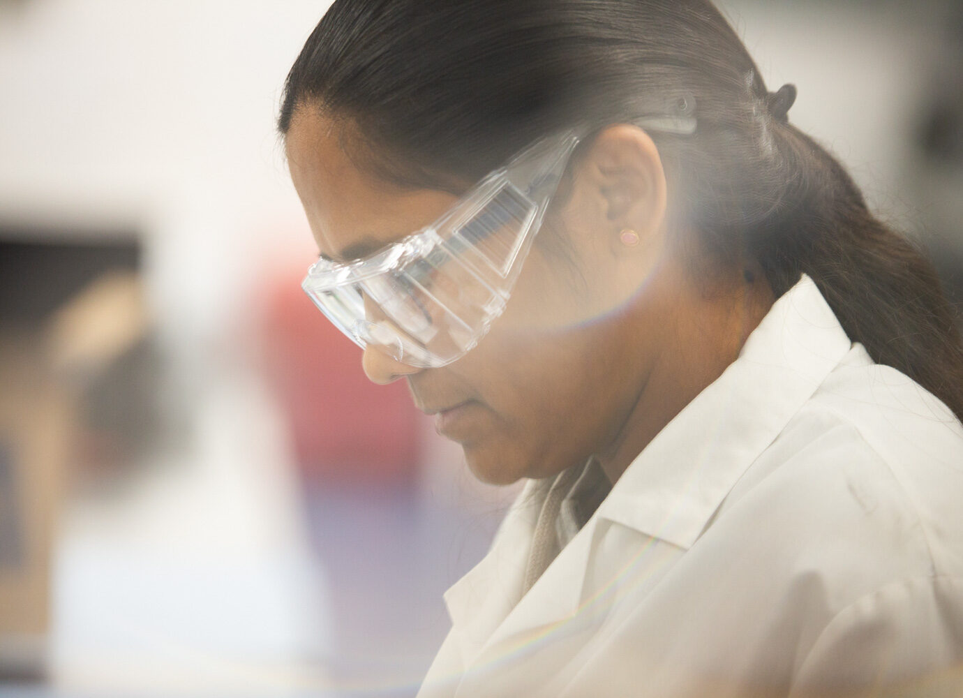 Profile of a female scientist wearing safety glasses in a laboratory
