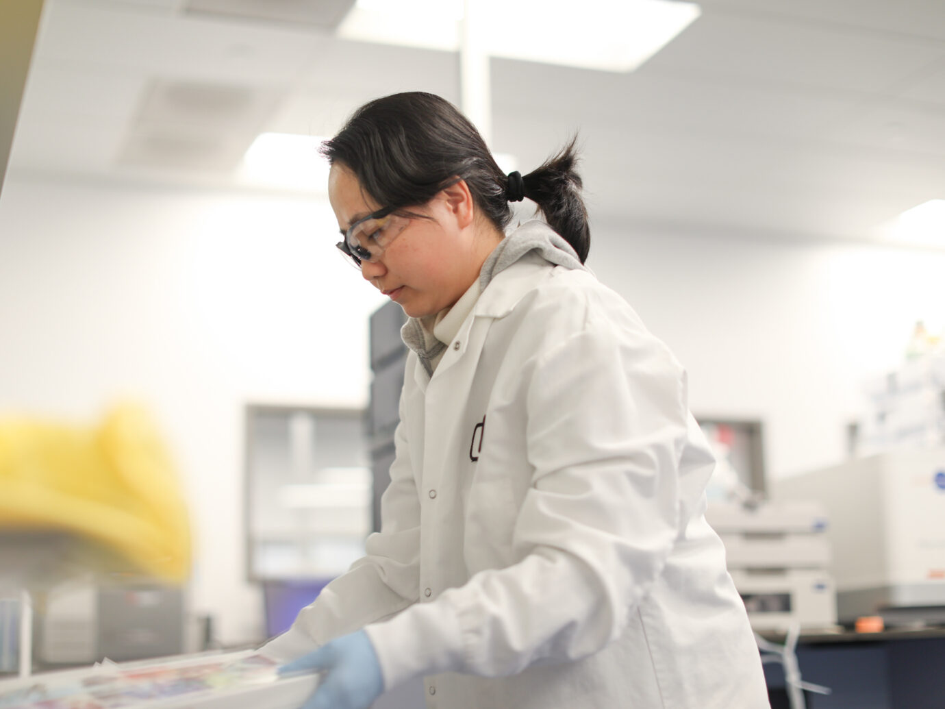 Female lab worker wearing safety glasses in profile in a laboratory