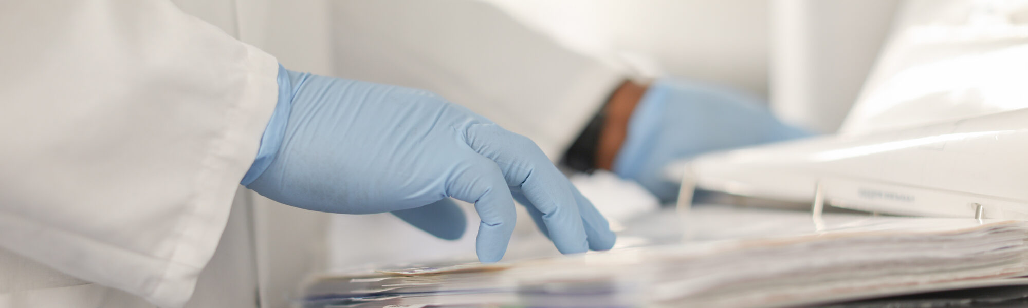 Gloved hand reaching for paperwork on a lab cart