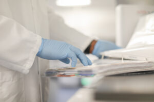 Gloved hand reaching for paperwork on a lab cart