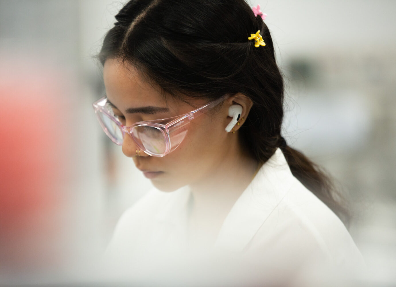 Young woman wearing pink glasses looking down in a lab setting