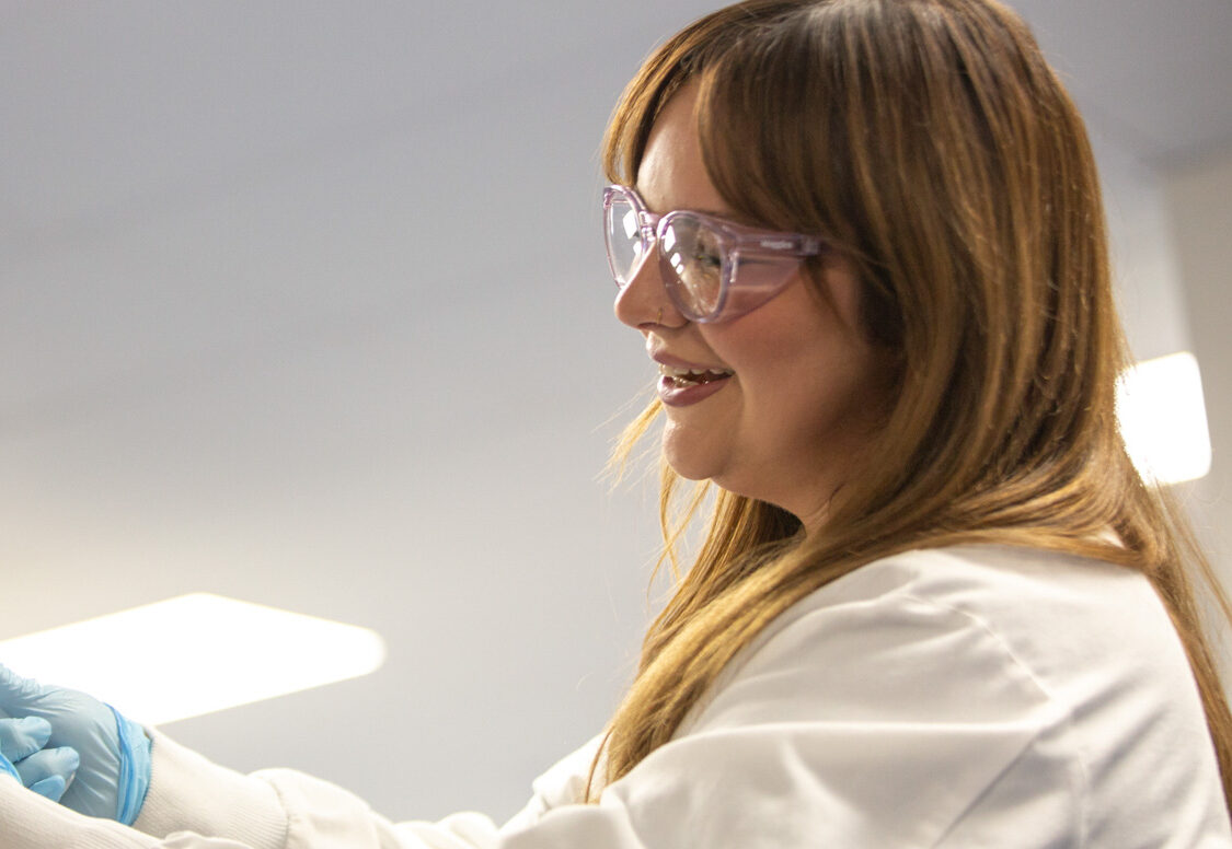 Profile of a smiling woman wearing safety glasses