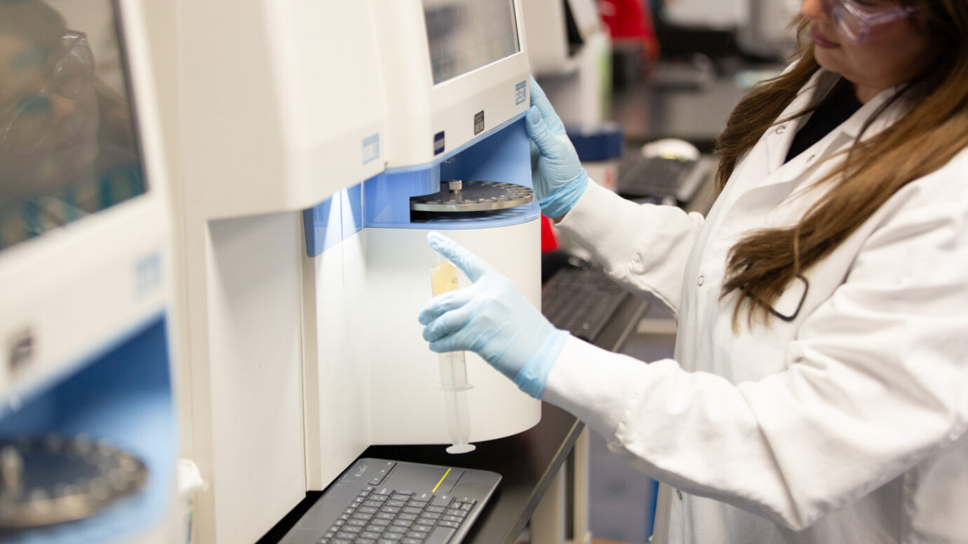 Female scientist wearing safety glasses examining bioprocessing equipment