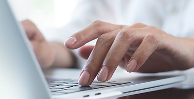 Close-up of hands typing on a laptop keyboard
