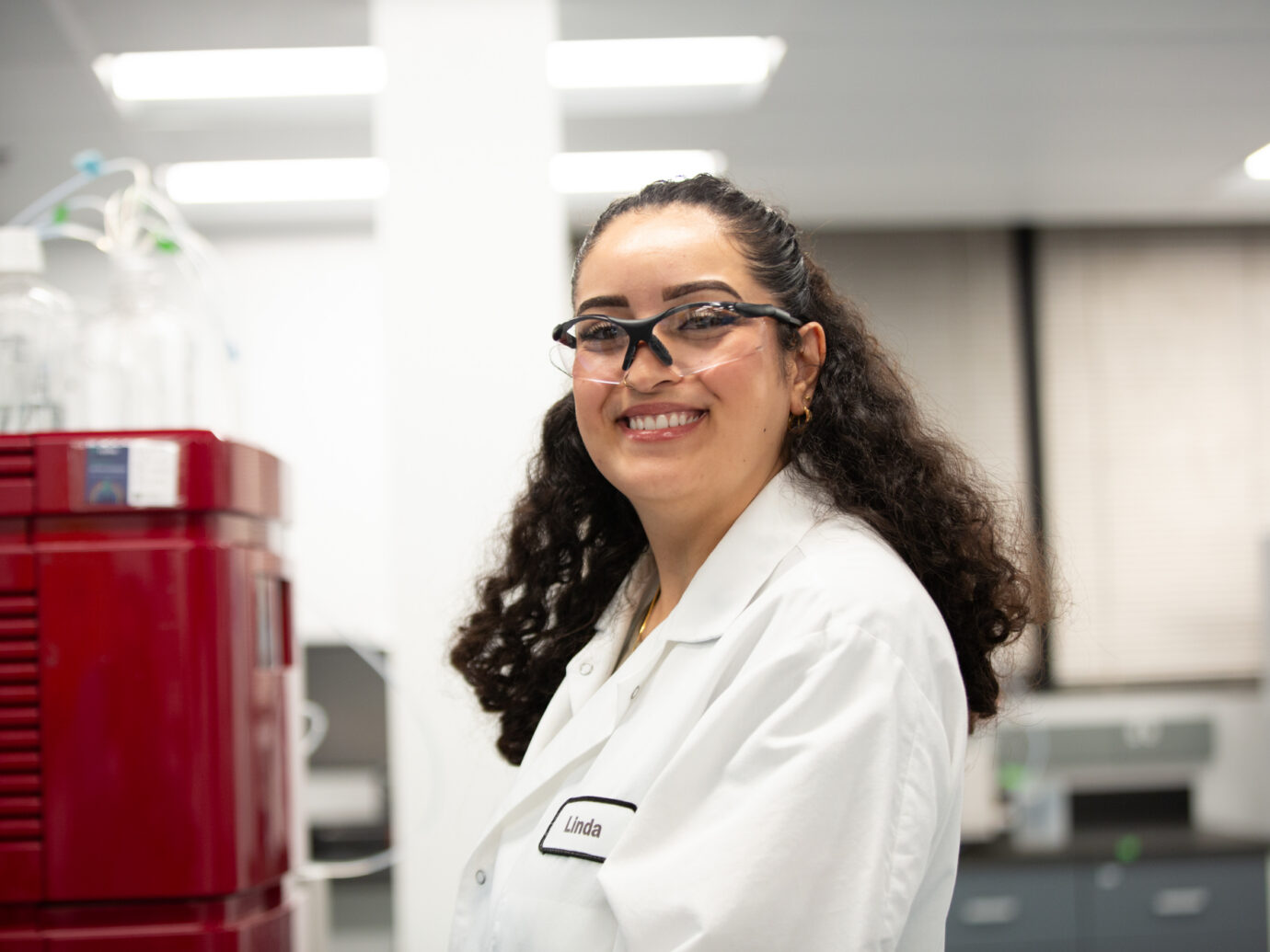 Smiling female scientist wearing safety glasses in a laboratory